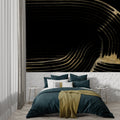 Black and gold abstract wallpaper creating drama in a modern living room with minimal furniture