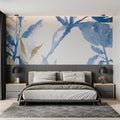 Blue and gold watercolor leaf wallpaper in modern living room with grey sofa and natural light