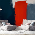 Abstract red and navy brushstroke wallpaper creating dramatic impact in a modern living room with white furniture