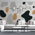 Modern abstract wallpaper with black and gold organic shapes creating a striking feature wall in a minimalist living room