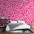 Pink geometric pattern wallpaper creating a modern statement wall in a bright, minimalist living room setting