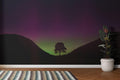 Aurora Borealis wallpaper mural shown in a modern living room, green and purple northern lights dancing above mountains