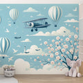 Hot air balloon wallpaper with cherry blossoms creating a magical atmosphere in a bright nursery with white furniture