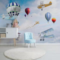 Aviation themed wallpaper in bright nursery with white furniture shows hot air balloons and vintage planes