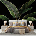 Tropical banana leaf wallpaper creating dramatic impact in a modern living room with black accent wall and gold accessories