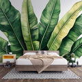 Tropical banana leaf wallpaper creating a fresh green backdrop in a modern living room with white furniture