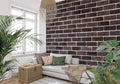 Brown brick wallpaper in modern living room with grey sofa and natural light