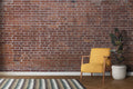 Red brick wallpaper creating an industrial accent wall in a modern living room with minimal furniture