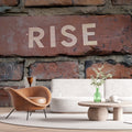 Industrial brick wallpaper with RISE typography shown in modern office space, creating an inspiring accent wall