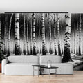 Black and white forest wallpaper creating depth in a modern living room with minimal furniture and natural light