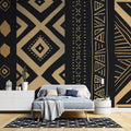 Black and gold geometric tribal wallpaper in modern living room creating dramatic accent wall with warm lighting