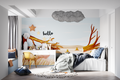 Forest wallpaper creating a cozy reading nook in a modern kids bedroom with natural light and wooden furniture