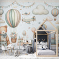 Hot air balloon nursery wallpaper in soft pastels shown in a bright children's bedroom with white furniture and natural light
