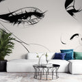 Line art face wallpaper mural creating a dramatic focal point in a modern minimalist living room with white furniture