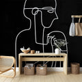 Line art face wallpaper creating dramatic contrast in a modern minimalist living room setting with white furniture