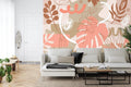 Modern living room with Monstera leaf wallpaper in coral and beige tones, creating a fresh botanical atmosphere