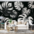 Modern living room with Black and White Monstera Leaf Wallpaper creating a stunning feature wall behind grey sofa