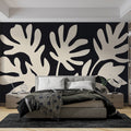Modern black and white Monstera leaf wallpaper in a bright living room with minimal furniture and natural light