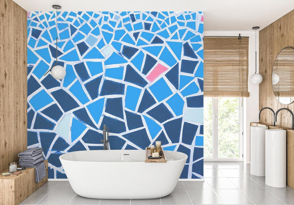 Modern blue geometric mosaic wallpaper with pink accents creating depth in a bright contemporary living room setting