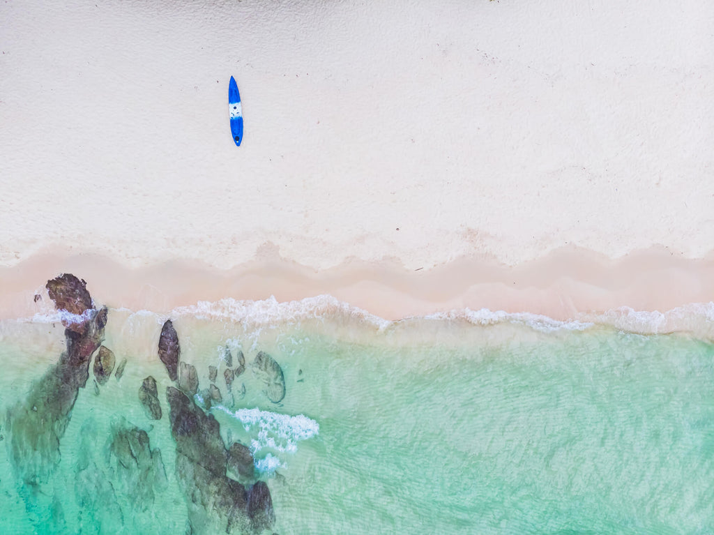Aerial beach design file showing turquoise waters meeting sandy shores with surfboard accent