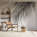 Black and white palm leaf mural wallpaper creating dramatic focal point in modern minimalist living room