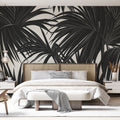 Black and white palm leaves wallpaper creating dramatic contrast in a modern living room with minimal furniture