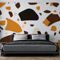 Modern Terrazzo Wallpaper with orange and brown pattern shown in a bright living room setting with minimal furniture