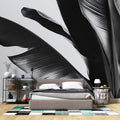Black and white tropical leaf wallpaper creating a stunning focal point in a modern minimalist living room with natural light