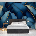 Blue and gold tropical leaf wallpaper creating luxury atmosphere in modern living room with grey sofa and brass accents