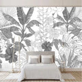 Modern black and white Monstera leaf wallpaper in a bright living room setting with minimal furniture