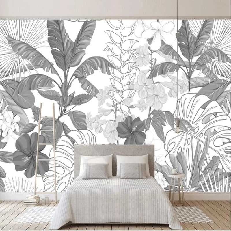 Modern black and white Monstera leaf wallpaper in a bright living room setting with minimal furniture