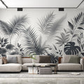 Black and white tropical leaf wallpaper creates drama in modern living room with gray sofa and natural light